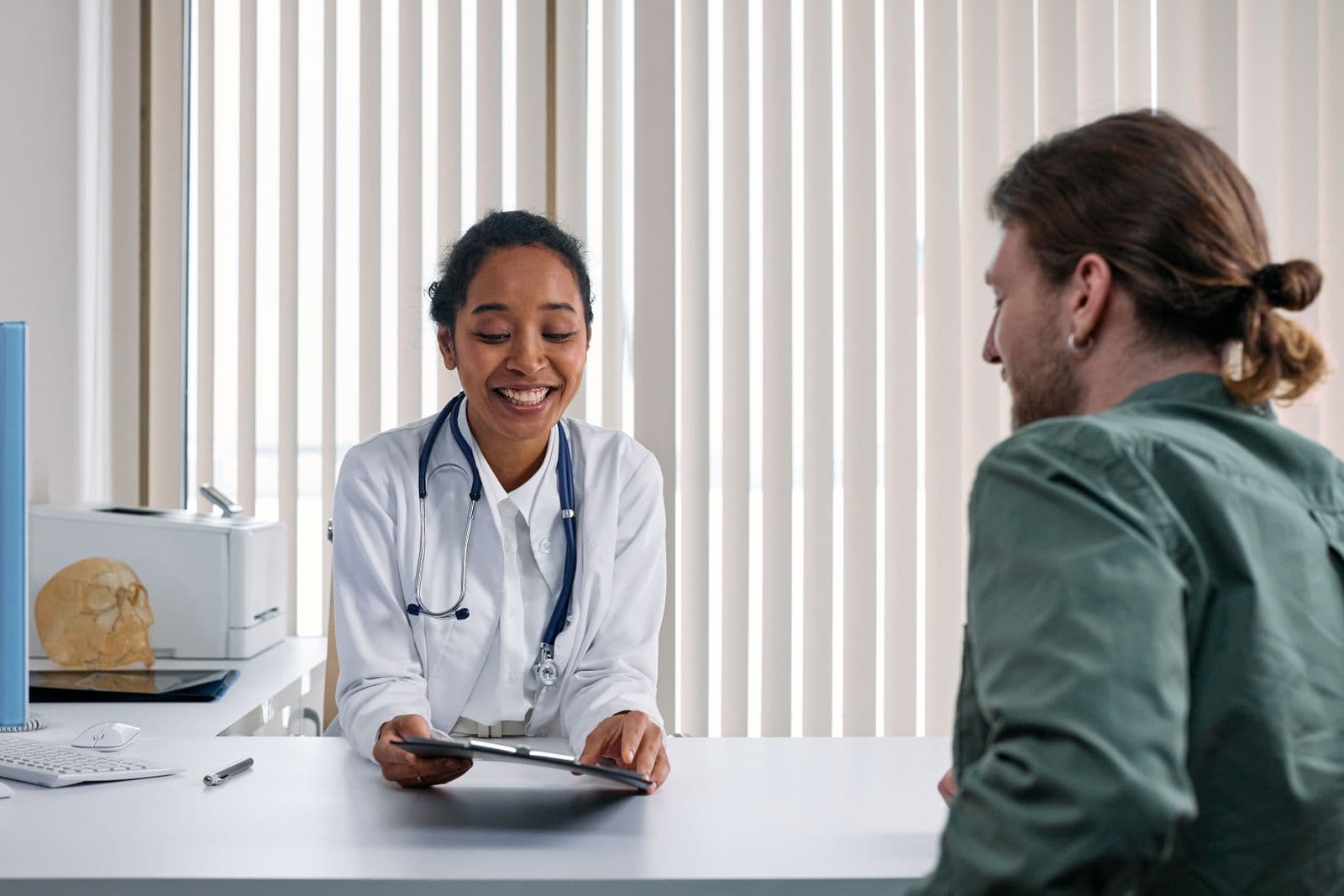 A smiling Caribbean doctor consulting with a patient at her desk
