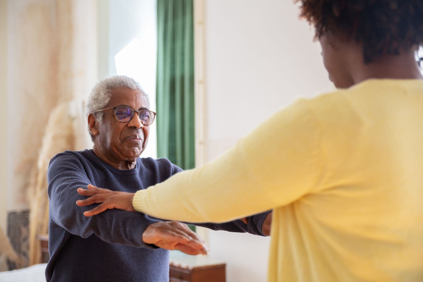 A Caribbean physiotherapist guiding an older patient through exercises